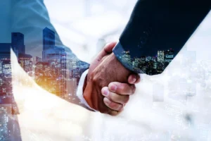 Business professionals shaking hands with a city skyline in the background, symbolizing partnership and collaboration.