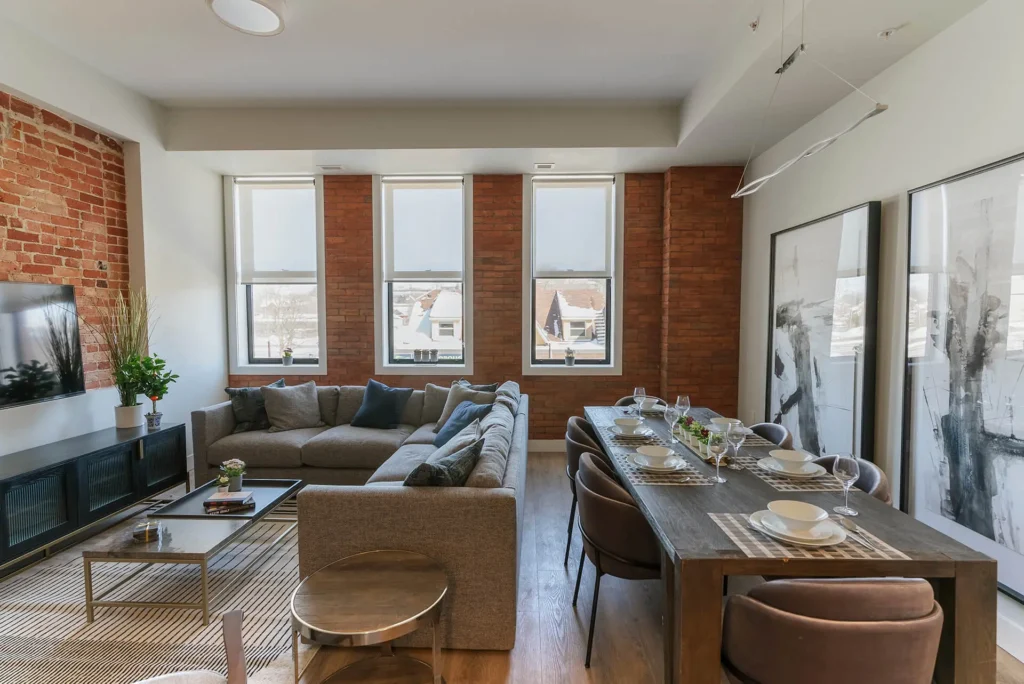 A modern kitchen in a loft apartment, featuring light wood cabinetry, stainless steel appliances, a white subway tile backsplash, and a large sink, suggesting a clean and functional cooking space.