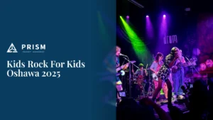 Picture of a band performing on an indoor stage with purple and green lights for an audience. On a dark blue background, the white text "Kids Rock For Kids Oshawa 2025" is displayed below the "PRISM PROPERTY MANAGEMENT" logo.
