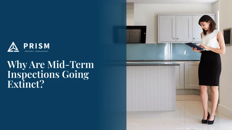 A woman in business attire stands in a modern kitchen with gray cabinets, looking down at a tablet she is holding. The image illustrates a property inspection alongside the question, "Why Are Mid-Term Inspections Going Extinct?"